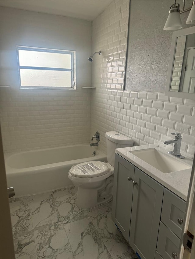 bathroom with marble finish floor, bathing tub / shower combination, a textured wall, toilet, and vanity