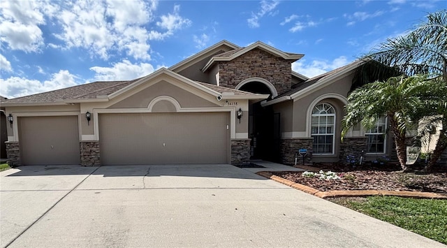 view of front of house with stone siding, concrete driveway, an attached garage, and stucco siding