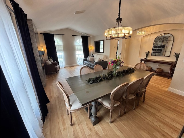 dining space featuring lofted ceiling, visible vents, light wood-style flooring, an inviting chandelier, and baseboards