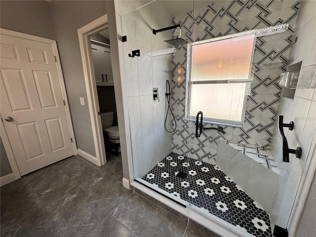 full bathroom featuring a stall shower, baseboards, and toilet