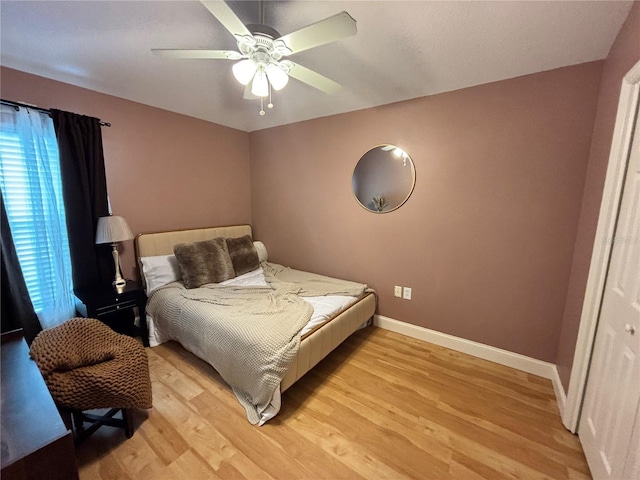 bedroom with light wood-type flooring, ceiling fan, and baseboards