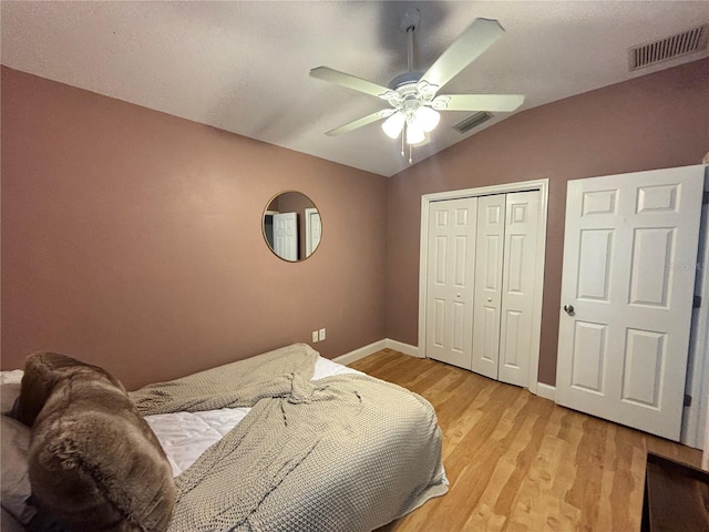 bedroom with lofted ceiling, light wood-type flooring, visible vents, and a closet