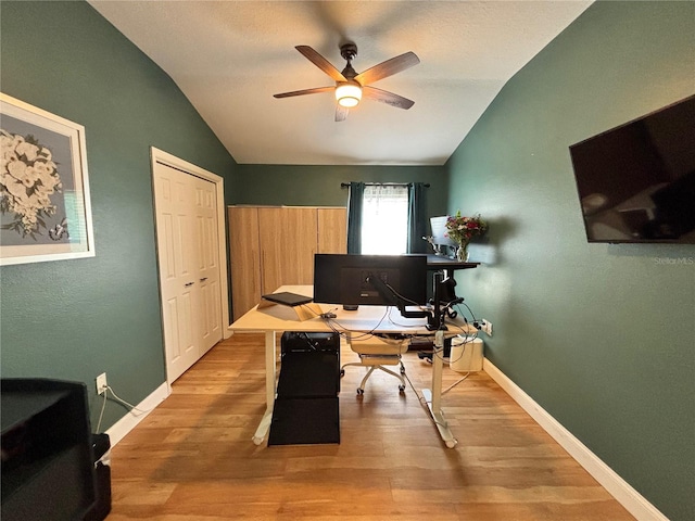 office area with light wood-style floors, vaulted ceiling, baseboards, and a ceiling fan