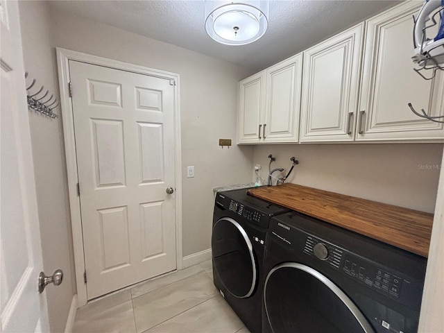 washroom featuring washing machine and dryer, cabinet space, and baseboards