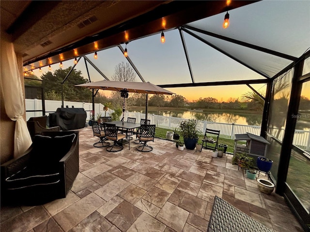 patio terrace at dusk with visible vents, a water view, a fenced backyard, and outdoor dining space