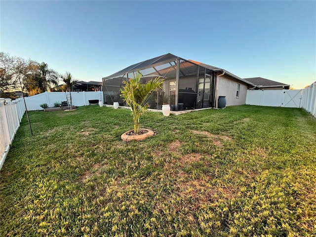 rear view of house with glass enclosure, a yard, and a fenced backyard