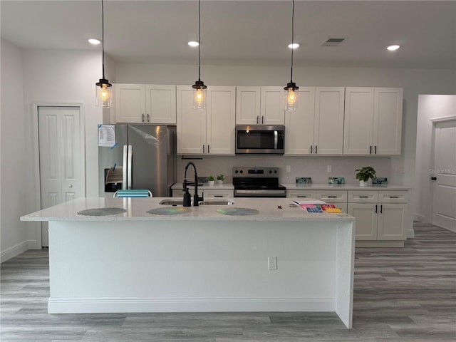 kitchen with visible vents, an island with sink, a sink, stainless steel appliances, and tasteful backsplash