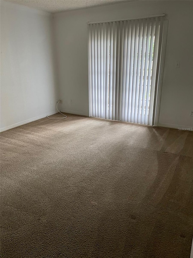 carpeted empty room with a textured ceiling