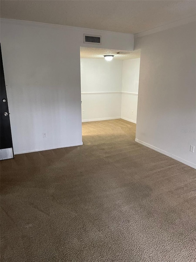 spare room featuring carpet, visible vents, baseboards, and ornamental molding