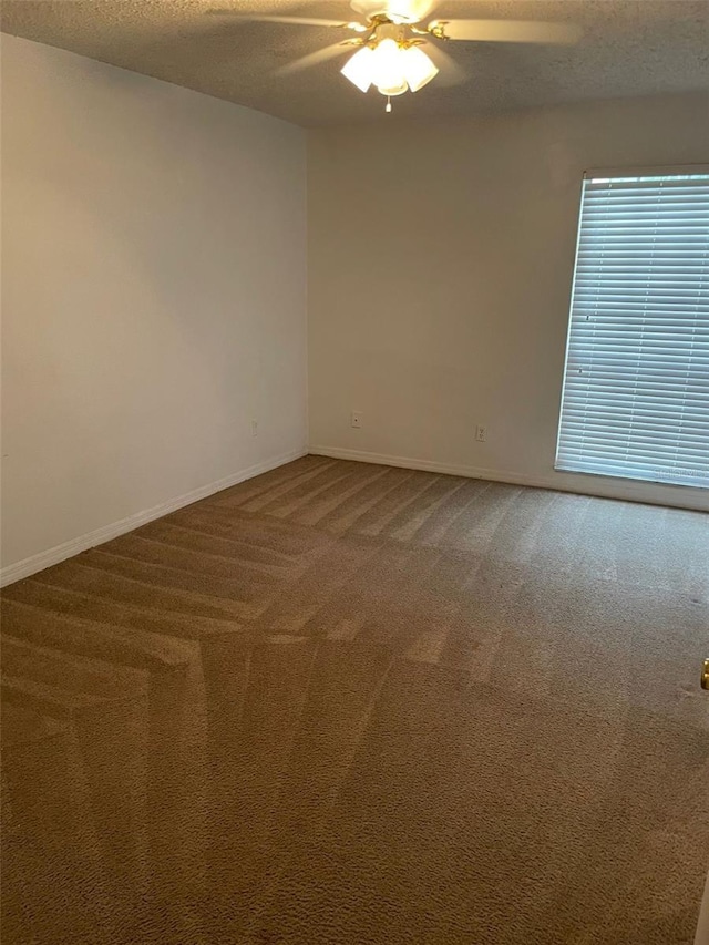 carpeted spare room featuring a ceiling fan, a textured ceiling, and baseboards