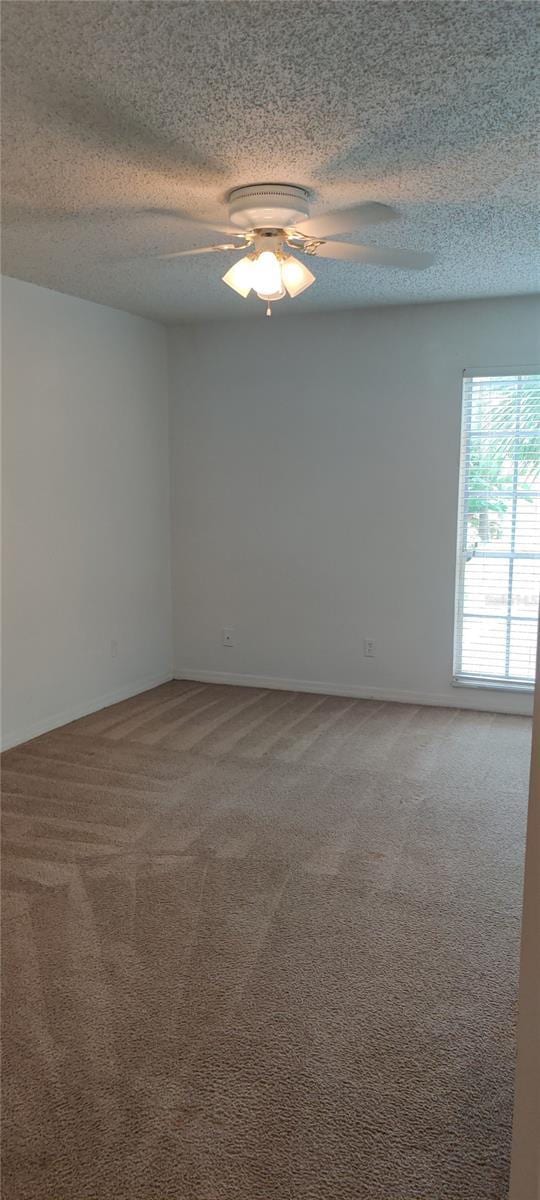 unfurnished room featuring ceiling fan, a textured ceiling, baseboards, and carpet flooring