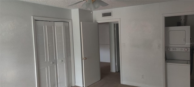 unfurnished bedroom featuring visible vents, stacked washer / dryer, ceiling fan, a textured ceiling, and a closet