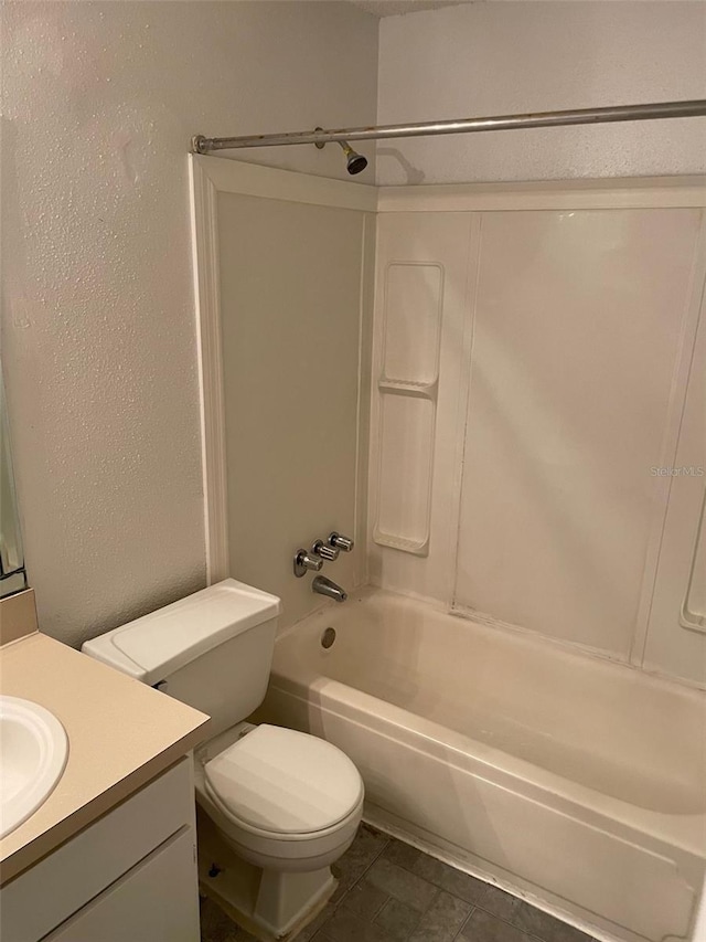 bathroom with shower / washtub combination, a textured wall, toilet, vanity, and tile patterned flooring