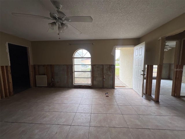 spare room with light tile patterned floors, ceiling fan, and a textured ceiling