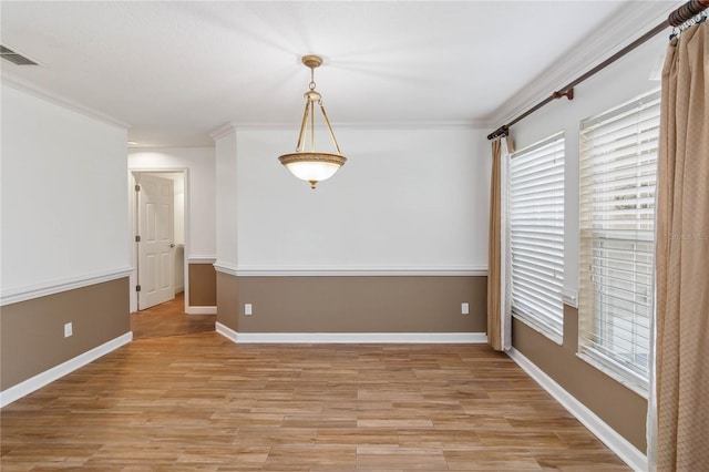 empty room featuring ornamental molding, baseboards, visible vents, and light wood finished floors