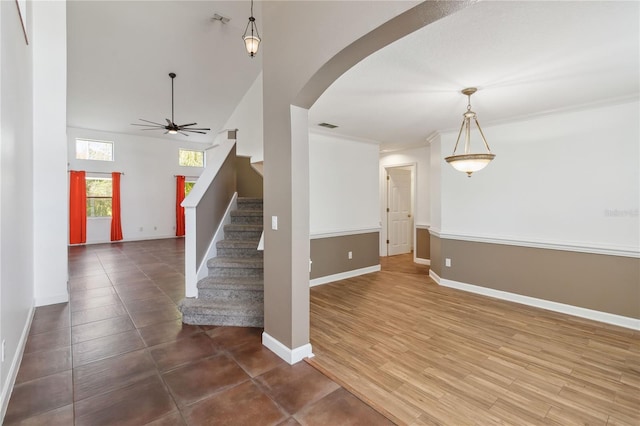 interior space featuring arched walkways, visible vents, ceiling fan, wood finished floors, and baseboards