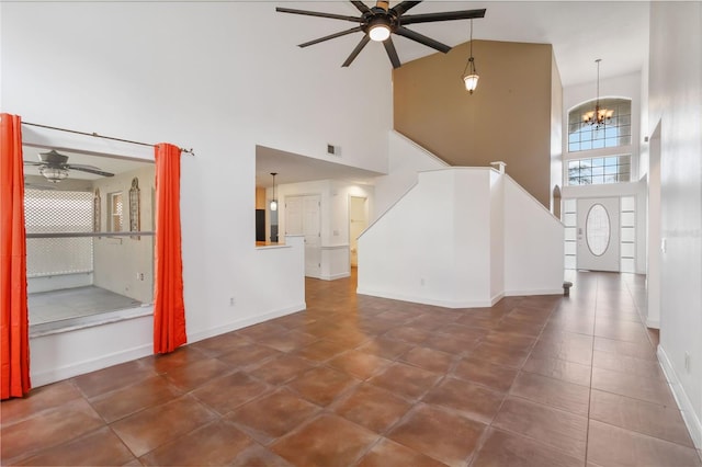 unfurnished living room with ceiling fan with notable chandelier, stairway, visible vents, and baseboards