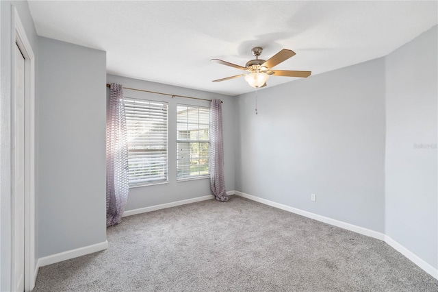 spare room with carpet floors, a ceiling fan, and baseboards