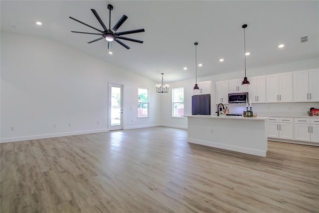 kitchen featuring light wood-type flooring, stainless steel microwave, open floor plan, and black fridge