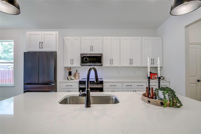 kitchen with white cabinets, a sink, stainless steel appliances, and light countertops