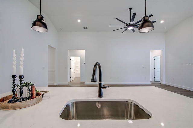 kitchen featuring visible vents, wood finished floors, decorative light fixtures, light countertops, and a sink