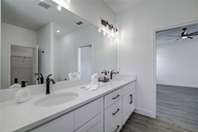 bathroom featuring double vanity, wood finished floors, a sink, and visible vents