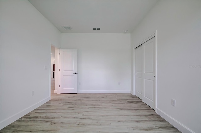 unfurnished bedroom featuring a closet, light wood-type flooring, visible vents, and baseboards