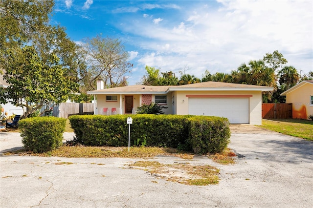 ranch-style house with a garage, driveway, and fence