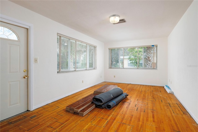 exercise area featuring a baseboard radiator, baseboards, and wood finished floors