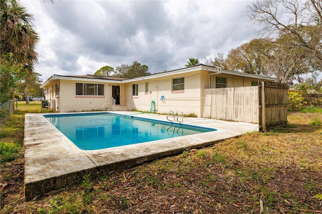 back of property with a fenced in pool and fence