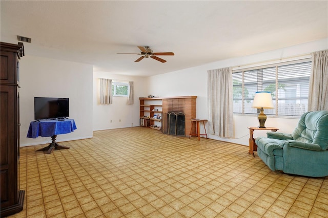 living area featuring light floors, a fireplace, visible vents, and baseboards