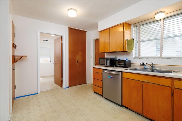 kitchen with light floors, appliances with stainless steel finishes, light countertops, and a sink