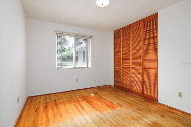 unfurnished bedroom with a closet, baseboards, and wood finished floors