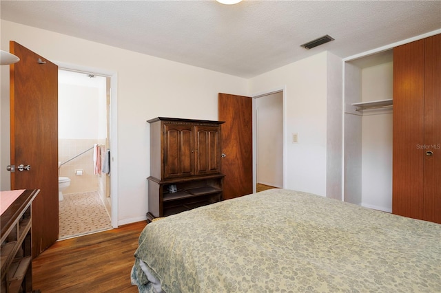 bedroom with a closet, a textured ceiling, visible vents, and dark wood-type flooring