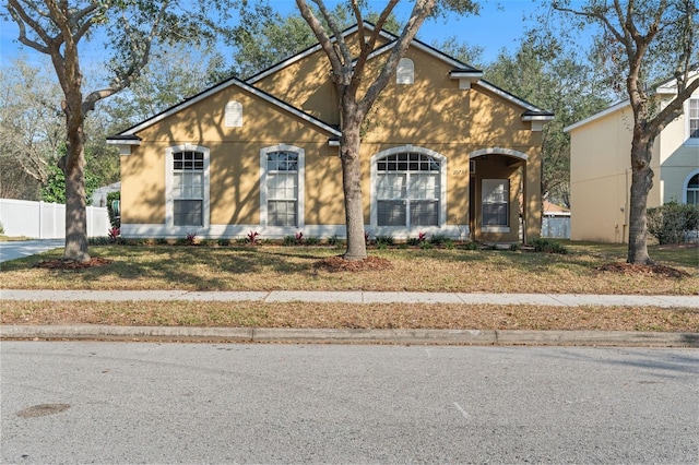 traditional-style house featuring a front yard and fence