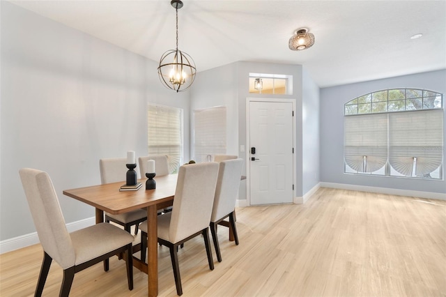 dining space featuring light wood finished floors, baseboards, and a chandelier