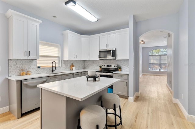 kitchen with a breakfast bar, light countertops, appliances with stainless steel finishes, a kitchen island, and a sink