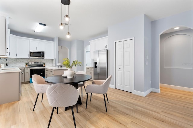 dining space featuring light wood-type flooring, baseboards, and arched walkways