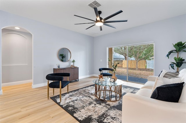 living room with arched walkways, visible vents, baseboards, and wood finished floors