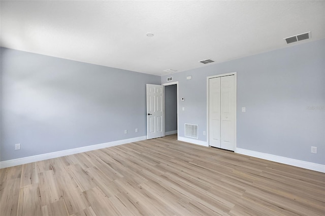 spare room featuring light wood-style floors, baseboards, and visible vents