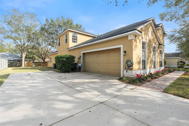 view of home's exterior featuring a garage, concrete driveway, fence, and stucco siding