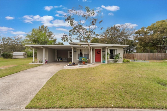 ranch-style home with an attached carport, fence, concrete driveway, stucco siding, and a front yard