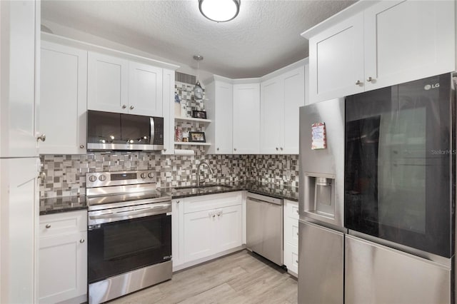 kitchen featuring appliances with stainless steel finishes, white cabinetry, a sink, and open shelves