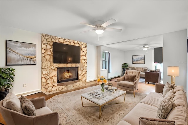 living room with a fireplace, wood finished floors, a ceiling fan, and baseboards