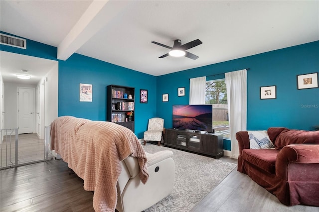 living room featuring beam ceiling, visible vents, ceiling fan, and wood finished floors