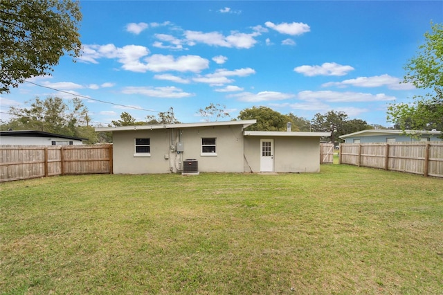 back of property featuring stucco siding, a fenced backyard, a lawn, and central air condition unit