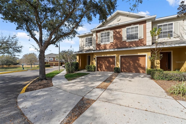 townhome / multi-family property with a garage, concrete driveway, and stucco siding