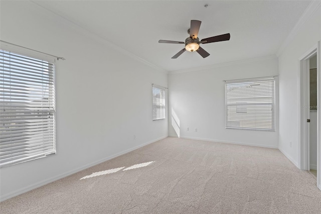 spare room with baseboards, light carpet, a ceiling fan, and crown molding