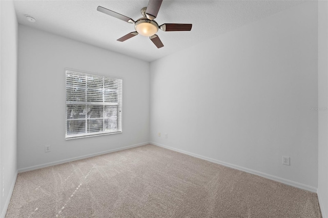 empty room with light colored carpet, a textured ceiling, and baseboards