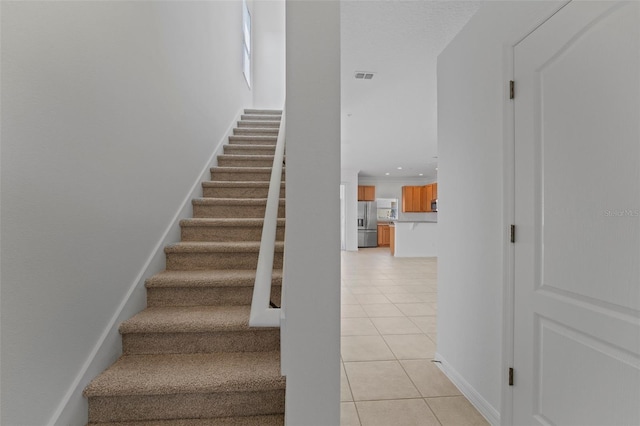 staircase featuring tile patterned flooring, visible vents, baseboards, and recessed lighting